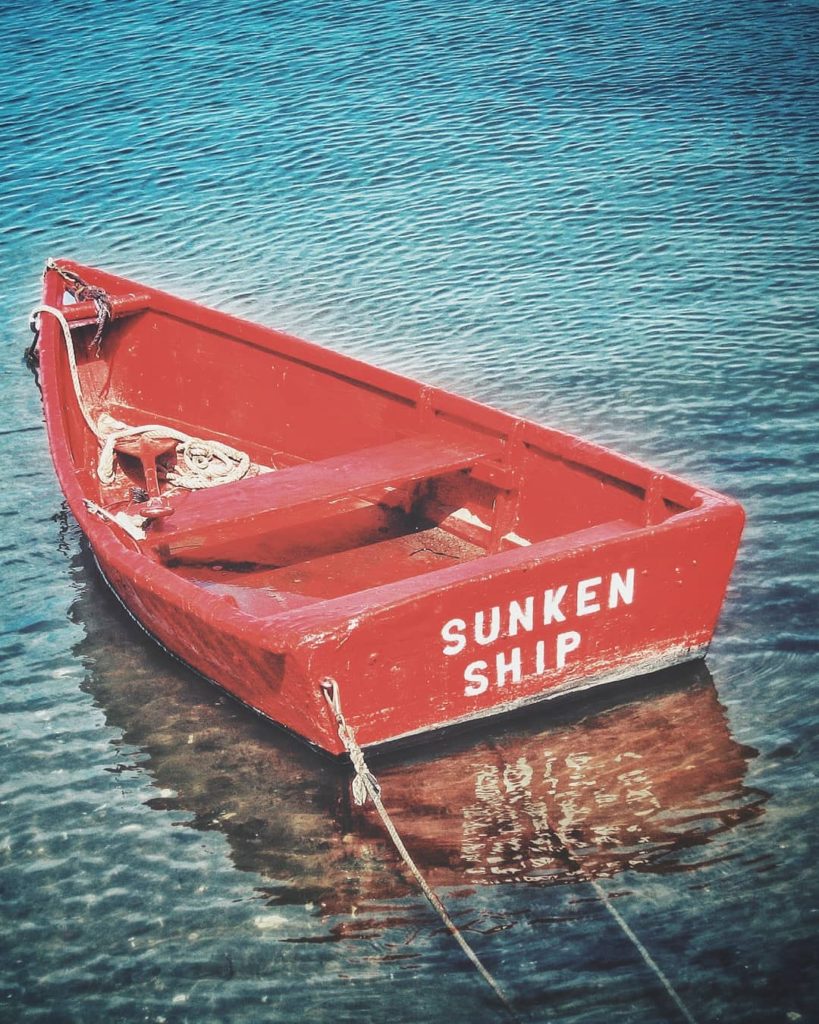 A rowboat with the word "sunken Ship" painted on it's back.